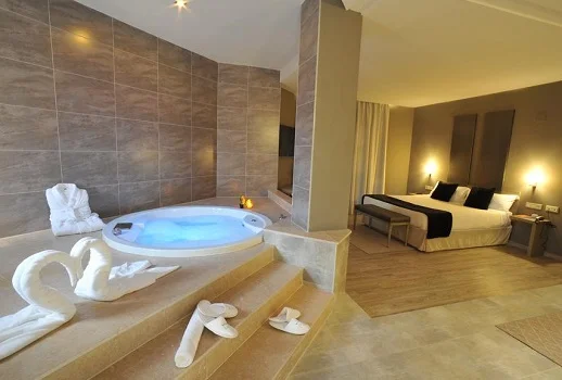 Foto de una de las habitaciones con jacuzzi del Hotel Luve donde se puede ver la cama al fondo y el jacuzzi a poca distancia de la cama.